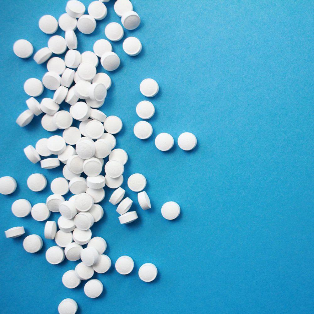 Many white pills shown against a blue background